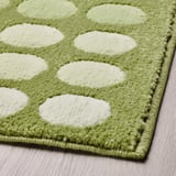 Alfombra de porta punteada verde e branca, textura suave, colocada nun chan de madeira.