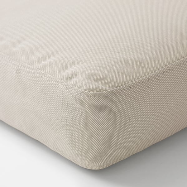 Primeiro plano dun coxín beige con tecido axustado, mostrando material suave e de alta calidade.