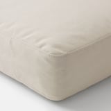 Primeiro plano dun coxín beige con tecido axustado, mostrando material suave e de alta calidade.