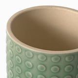 Primeiro plano dunha plantadora texturizada e verde menta, que mostra a súa calidade de gres manchado.