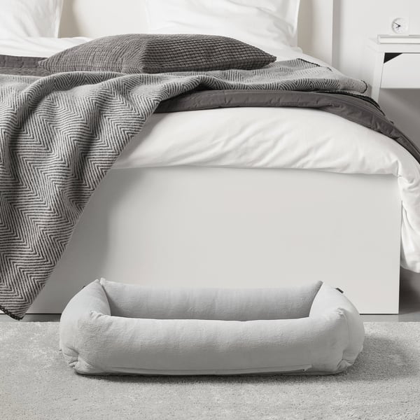 Unha cama suave preto dunha cama, con lados elevados para comodidade e apoio, ideal para cans de ata 20 kg.