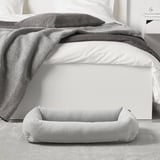 Unha cama suave preto dunha cama, con lados elevados para comodidade e apoio, ideal para cans de ata 20 kg.