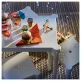 Os nenos xogan á mesa con comida, bebidas e avión de xoguete; cor branca, material plástico, forma cadrada.
