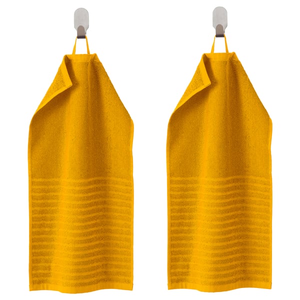 Dúas toallas VÅGSJÖN amarelas brillantes colgan un lado a outro en ganchos, rectangulares con bordos dobrados.