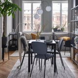 Zona de comedor moderna con mesa VANGSTA negra extensible, cadeiras grises e grandes fiestras.