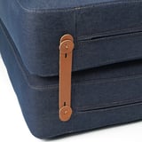 Primeiro plano dunha elegante cama de cadeira de denim con robustas correas de coiro marrón e fixacións metálicas seguras, mostrando artesanía de alta calidade.