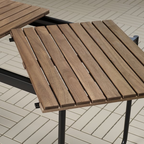 Mesa exterior de madeira con tapa de lama e patas de metal negro, deseñada para durabilidade e fácil almacenamento.