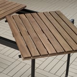 Mesa exterior de madeira con tapa de lama e patas de metal negro, deseñada para durabilidade e fácil almacenamento.