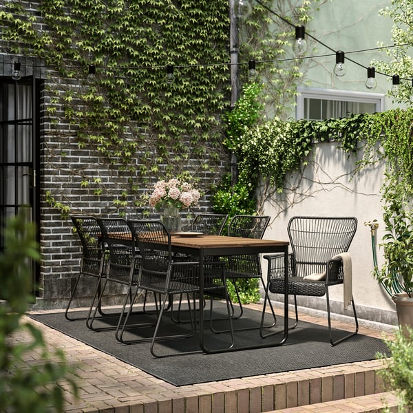 Conxunto moderno de patio exterior con mesa e cadeiras de metal negro, perfecto para cear.