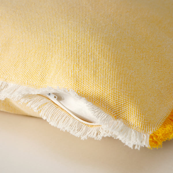 Unha cuberta de coxín amarelo brillante con franxas brancas e cremalleira, mostrando un tecido texturizado.