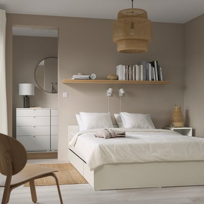 Dormitorio minimalista: paredes beige, cama branca, luz colgante, espello, cadeira.