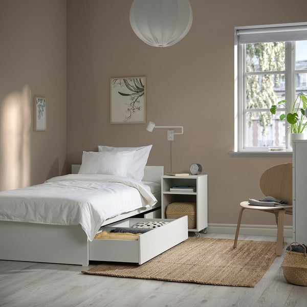 Dormitorio con cama VIHALS , dúas caixas de almacenamento, paredes marróns, planta.