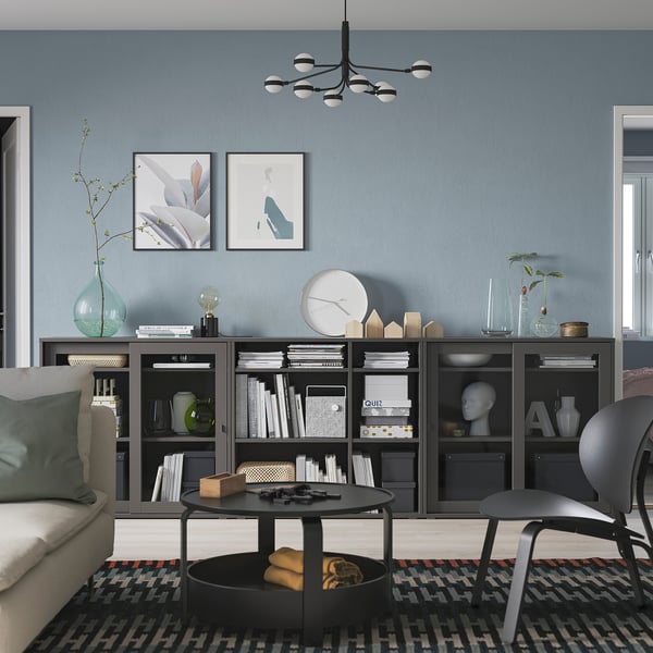 Sala de estar moderna con librería negra, decoración e asentos acolledores.