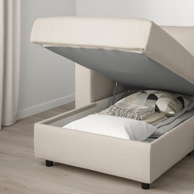 Sofá VIMLE de cor crema con almacenamento. A chaise longue ten unha tapa aberta que revela almofadas no interior.
