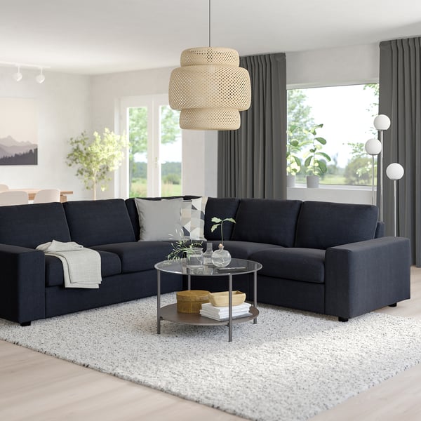 Sala de estar moderna con mesa de café VIMLE sectional, ottoman, de vidro, luz pendente, plantas e luz natural.