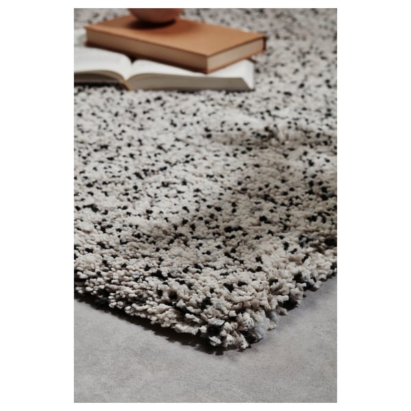Primeiro plano de elegante alfombra VINDUM con manchas negras en branco, pila grosa suave, libros na parte superior.