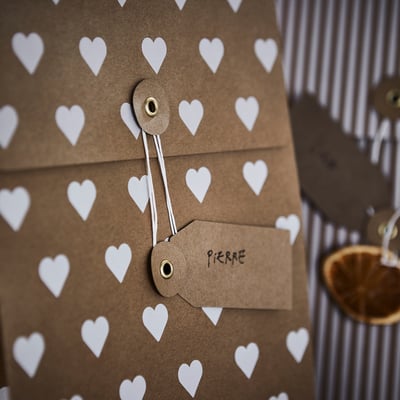 Dúas bolsas de papel marrón con lazos de corda, unha a raias e outra con corazóns. Ecolóxico e elegante para agasallos ou delicias.