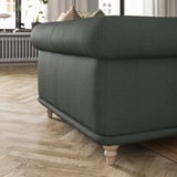 Cadeira de brazos VISKAFORS tapizada verde escuro con curvas suaves e pernas de madeira.