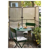 Pequena configuración de balcón con pantalla verde YTTERSKÄR, mesa e cadeiras, creando un espazo exterior acolledor.