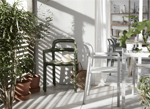 Två YPPERLIG stolar i grått och grönt står på en uteplats med grönska och skuggspel.