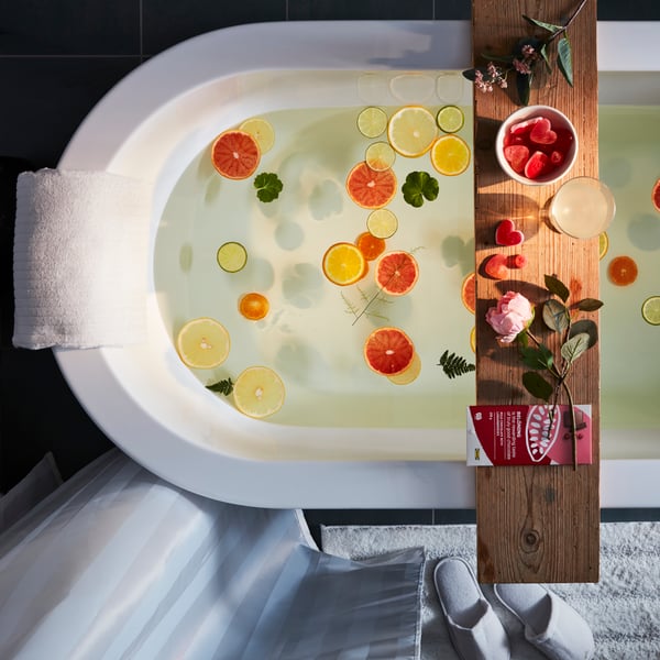 Een romantisch bad met zachte handdoek, slippers en wat lekkers te eten en te drinken