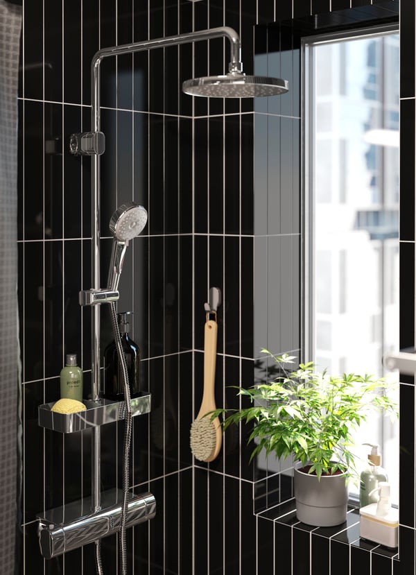 Blick auf eine schwarz gehaltene Dusche mit modernen Badarmaturen.