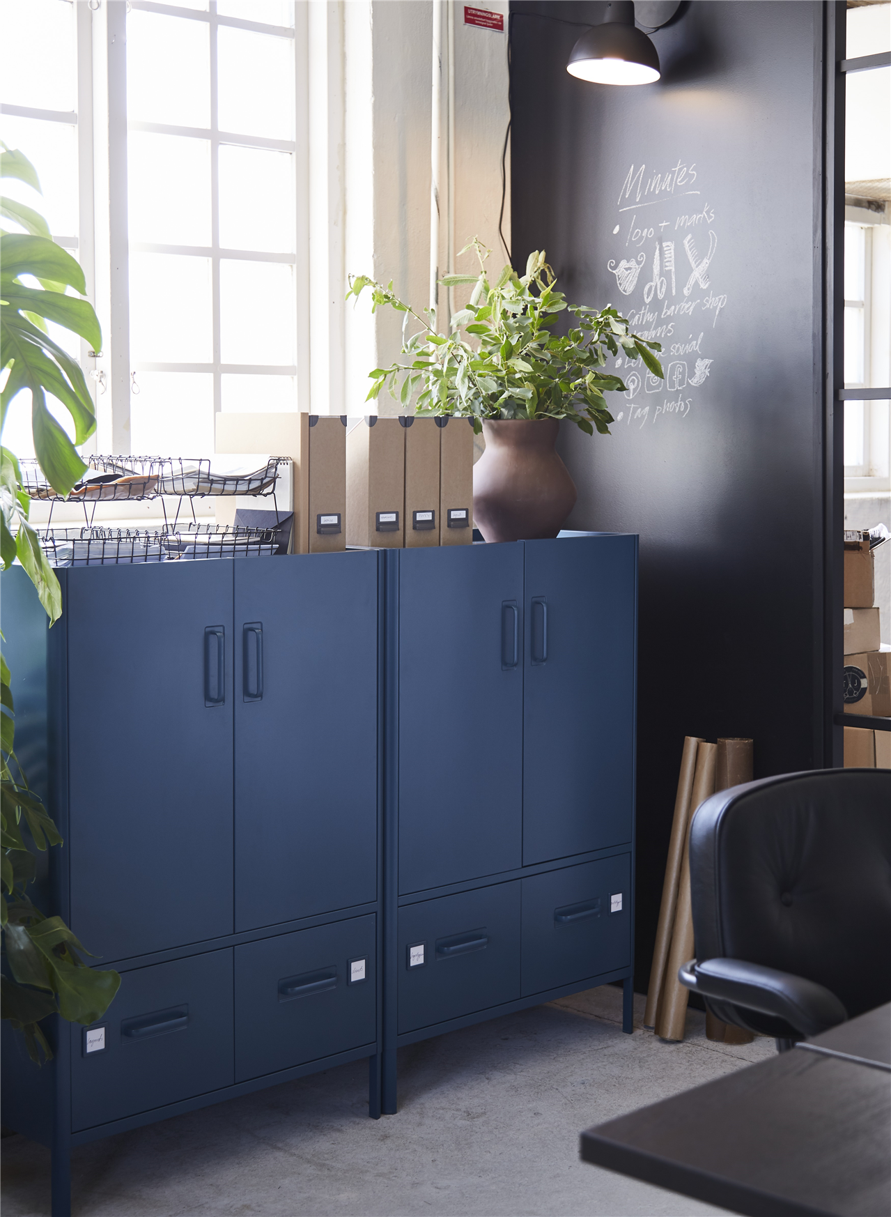 خزائن IDÅSEN أزرق داكن مع درجين أسفل كل وحدة، مع نباتات في أواني وأغراض متعددة من أعلى.