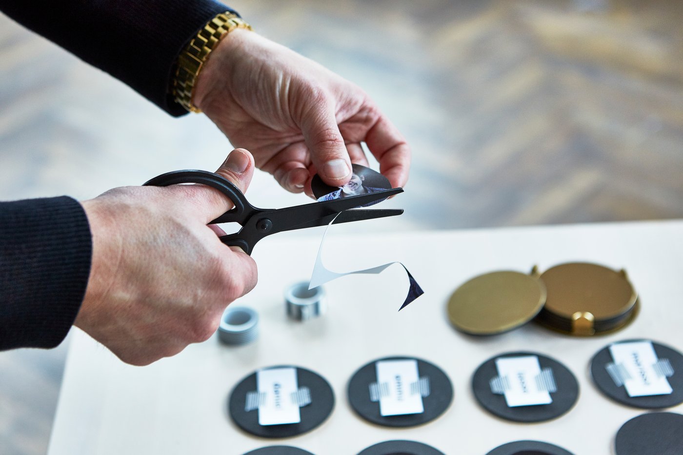 Someone cuts out photos with a black FULLFÖLJA pair of scissors and turns gold-coloured GLATTIS coasters into their own memory game.