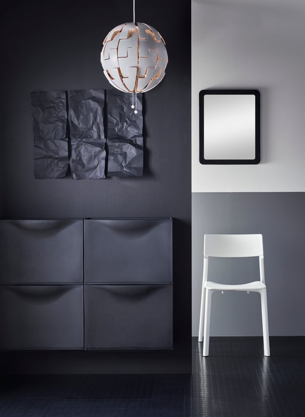 Black shoe cabinet TRONES next to a white JANINGE chair.