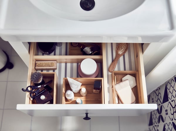 Wnętrze górnej szuflady szafki pod umywalkę, wypełnione bambusowym zestawem łazienkowym IKEA DRAGAN, 4 szt., z akcesoriami łazienkowymi. 