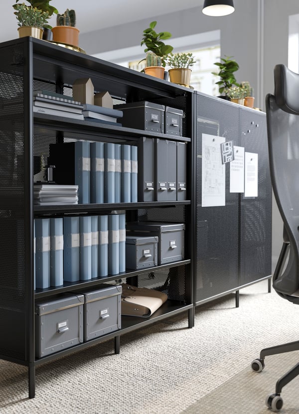 BEKANT black office shelving unit used as a divider, with paper reminders attached to its magnetic mesh door.