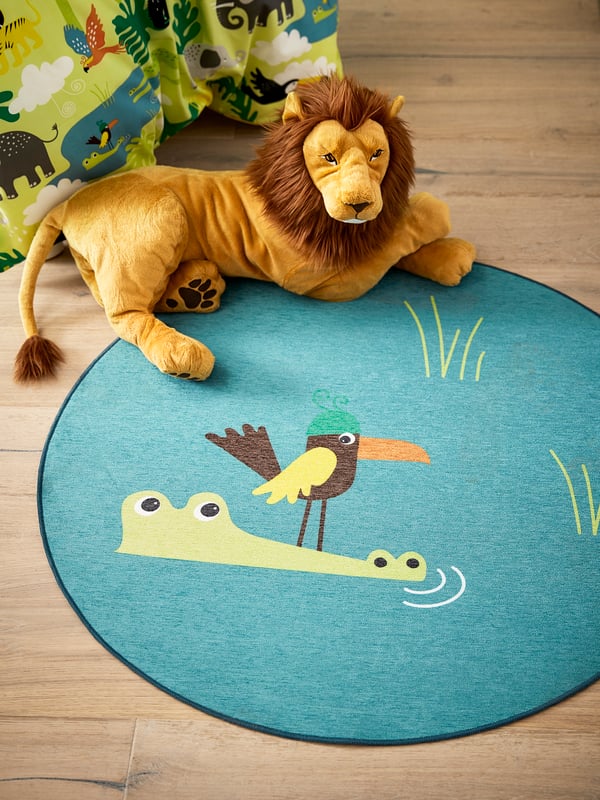 Un león de  peluche sobre un tapete infantil IKEA.