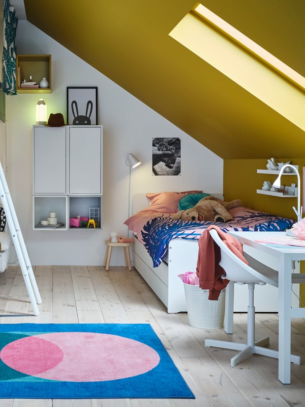 A white SLÄKT bed in a bedroom with a slanted, yellow coloured roof.