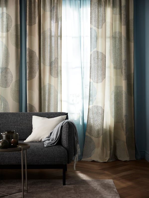 Eine SANDÄNGSFLY Gardine hängt hinter einer lichtdurchlässigen Gardine. Beide sorgen für unterschiedlichen Lichteinfall im Wohnzimmer. 