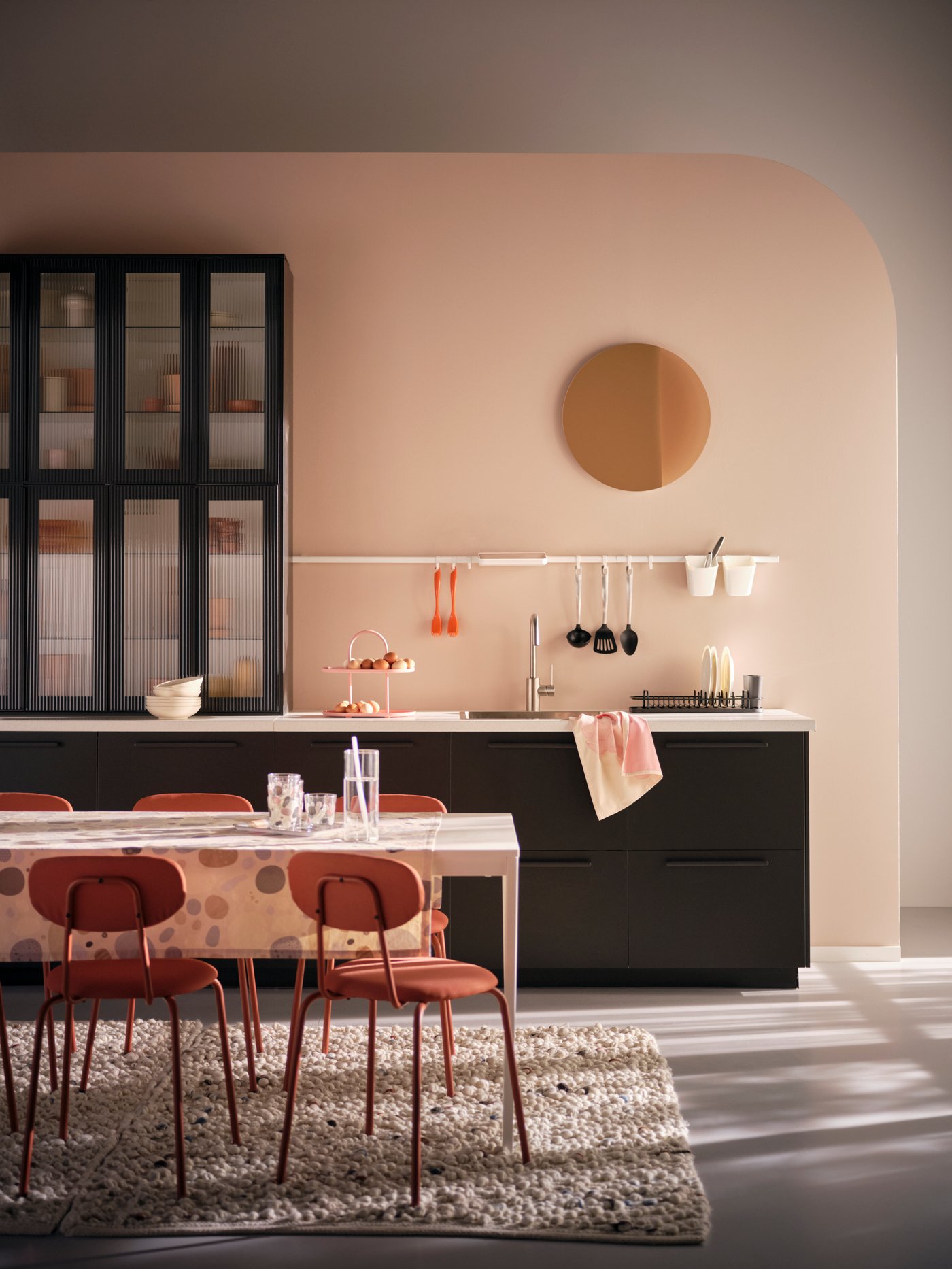 A kitchen with black fronts, ÖSTANÖ chairs in SUNDIAL and a white kitchen table