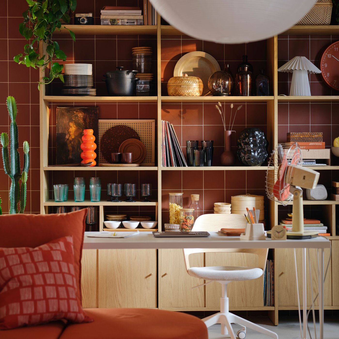 A LÅDMAKARE storage with cabinets with sliding doors stands by a reddish-brown wall, its shelves filled with various items.