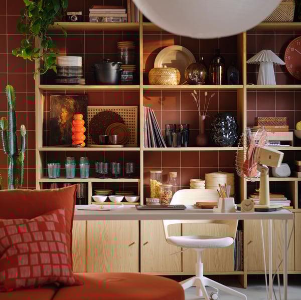 A LÅDMAKARE storage with cabinets with sliding doors stands by a reddish-brown wall, its shelves filled with various items.
