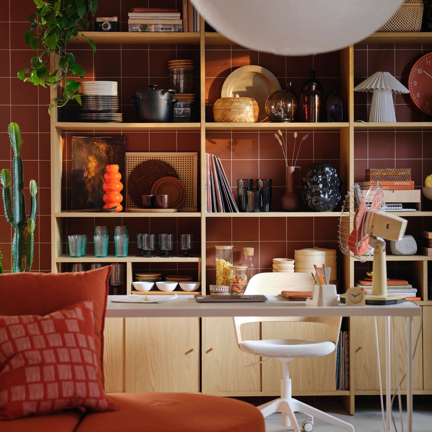 En LÅDMAKARE förvaring med skåp med skjutdörrar står mot en rödbrun vägg, och dess hyllor är fyllda med olika föremål.