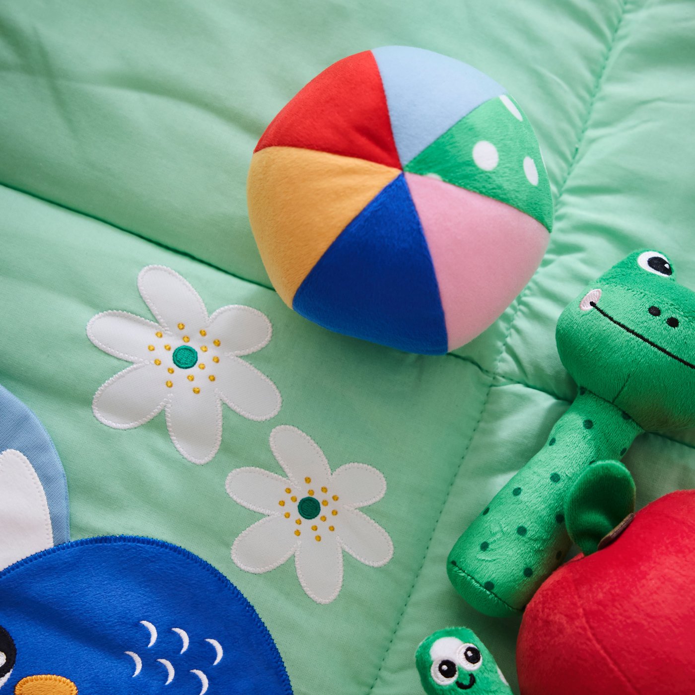 Close-up of colourful SANDBI rattle, soft toy and musical toy on top of SANDBI play mat.