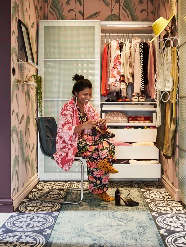 Girl trying on some heels sat in front of a wardrobe full of clothes.