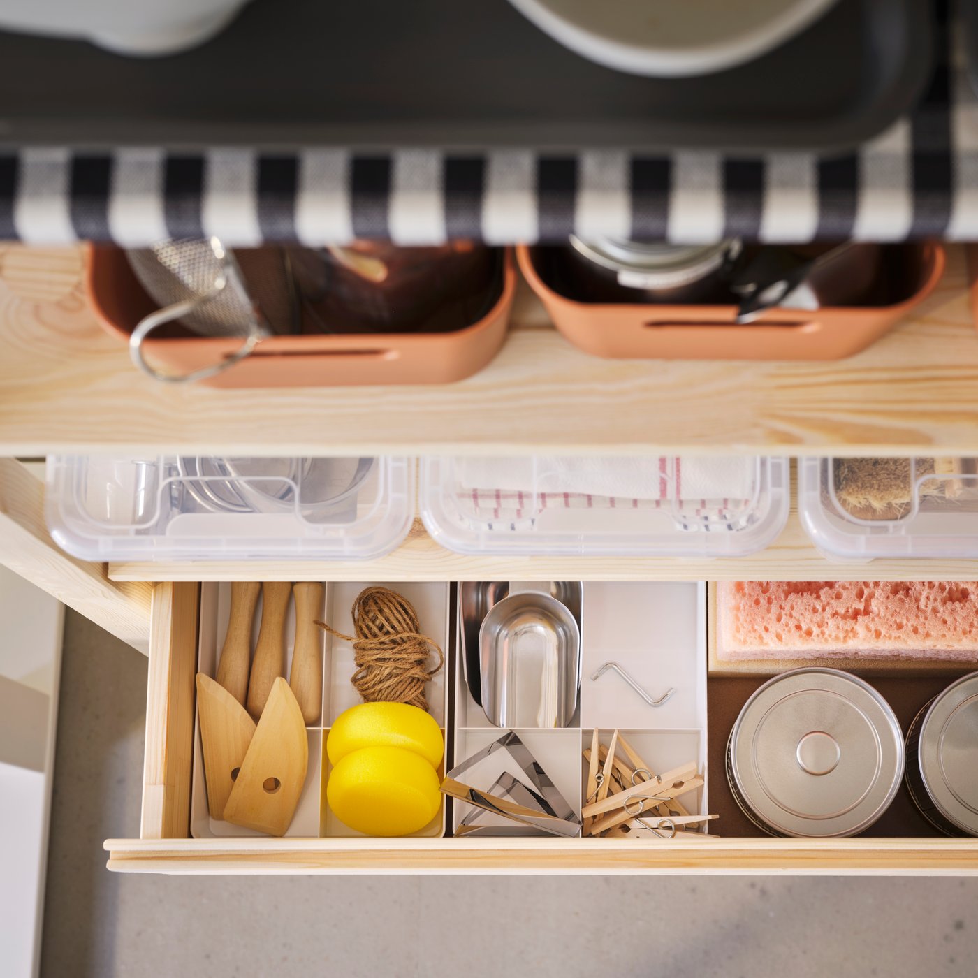 An open drawer with pottery tools and accessories organised in a KUGGIS insert. A shelf above the drawer holds SAMLA boxes.
