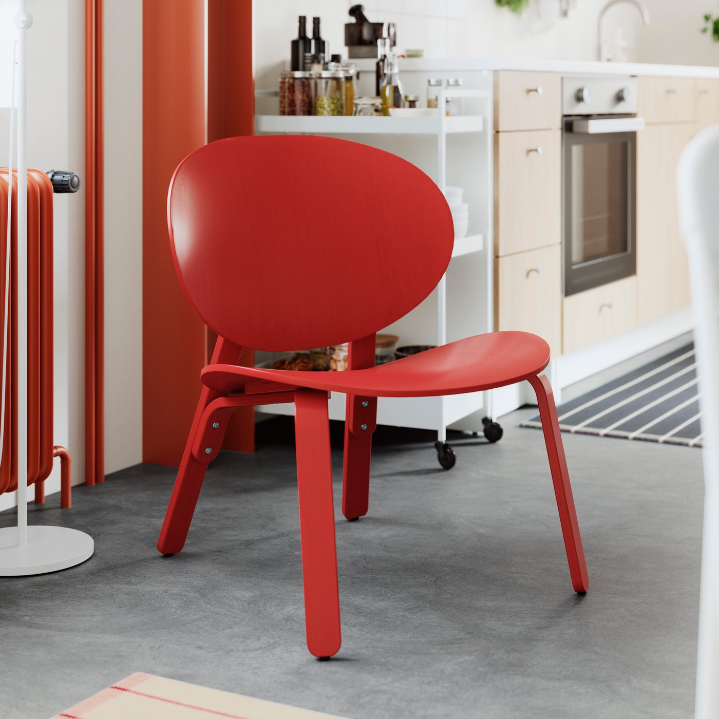  مطبخ به كرسي مريح FRÖSET من قشرة خشب بلوط مصبوغ بلون أحمر، وتوجد في الخلف زجاجات على عربة. 