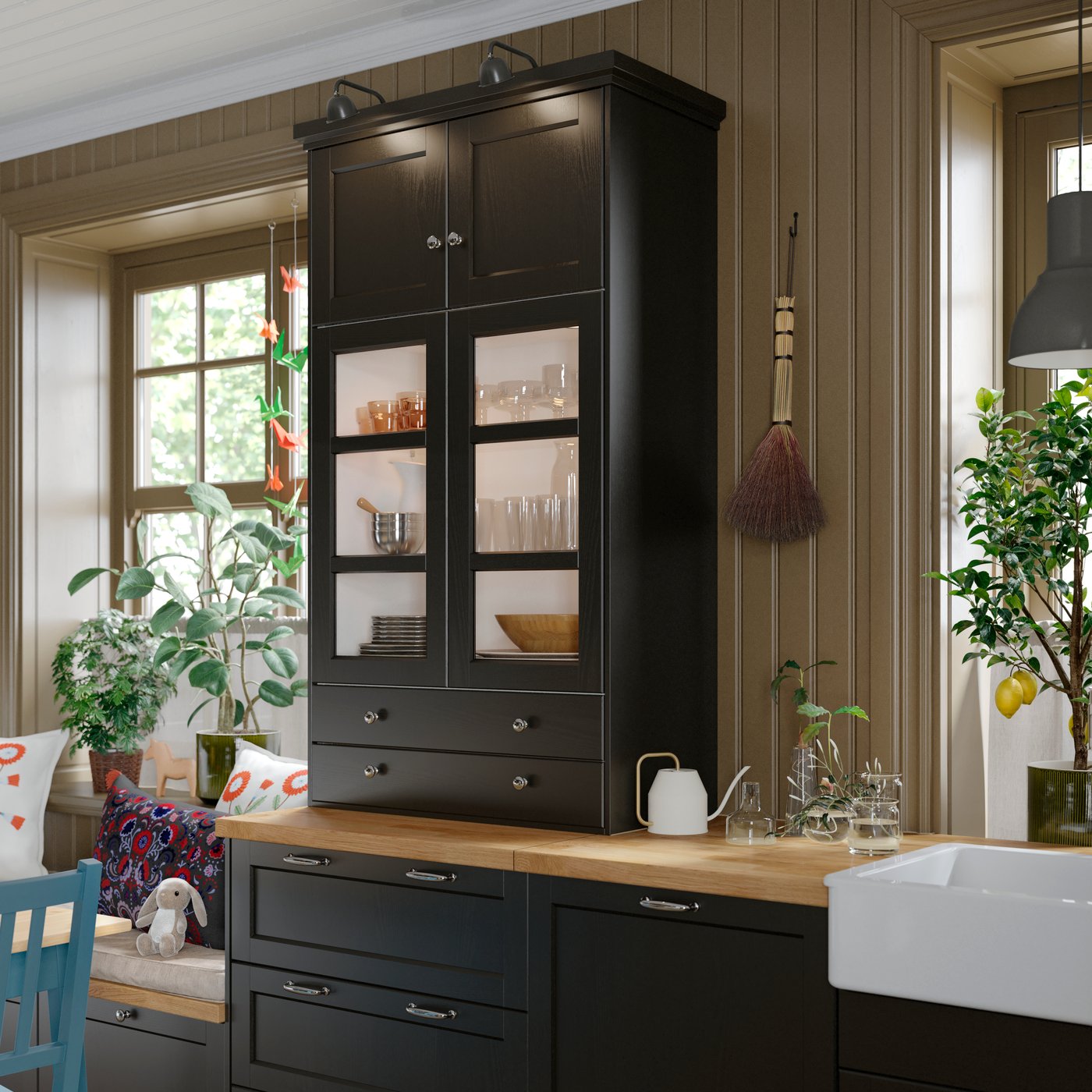 A kitchen with a black stained LERHYTTAN glass door cabinet displaying glassware and tableware, against wooden walls.