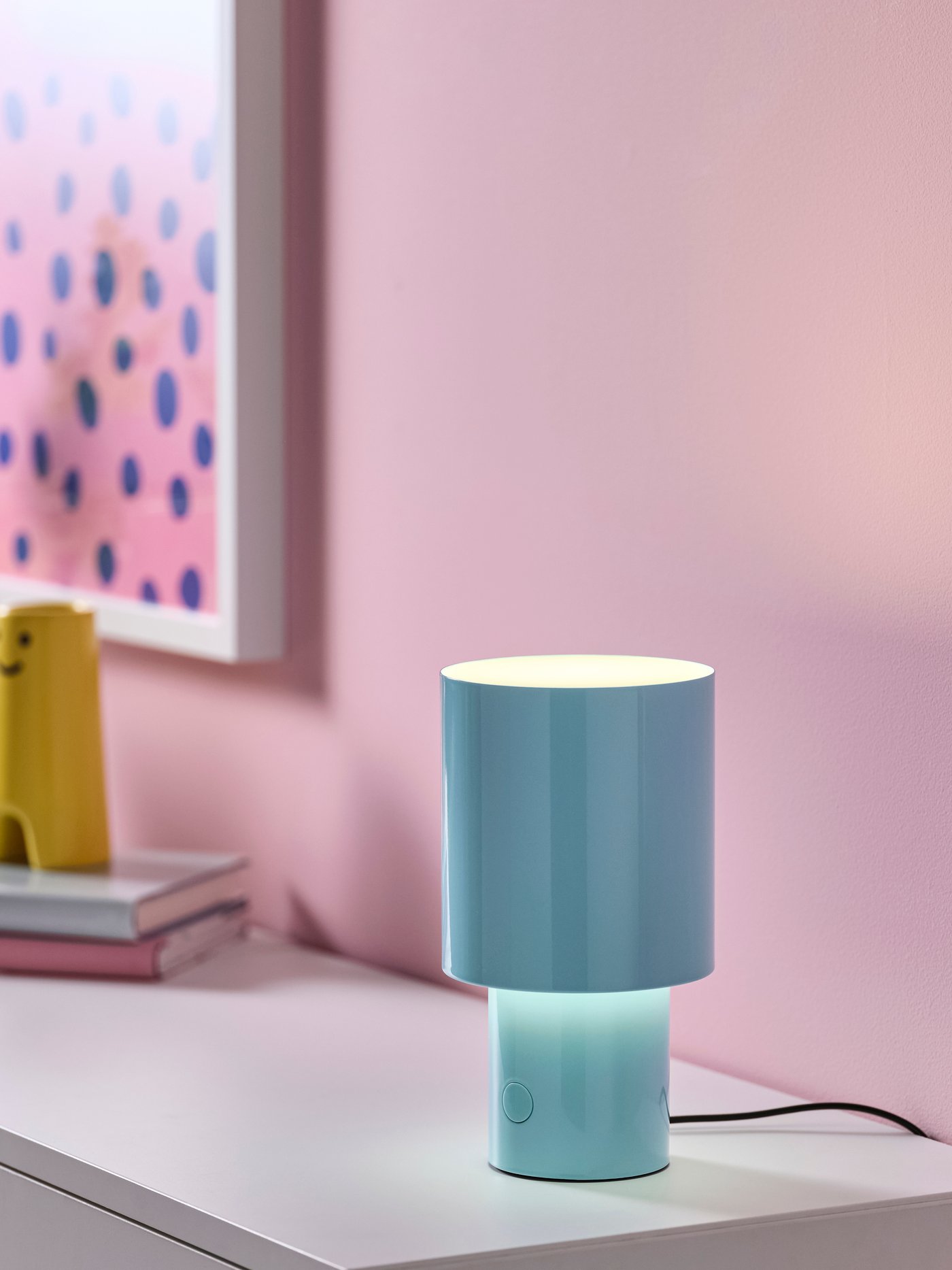 Eine dimmbare, hellblaue SPETSBOJ-Tischlampe im Wohnzimmer