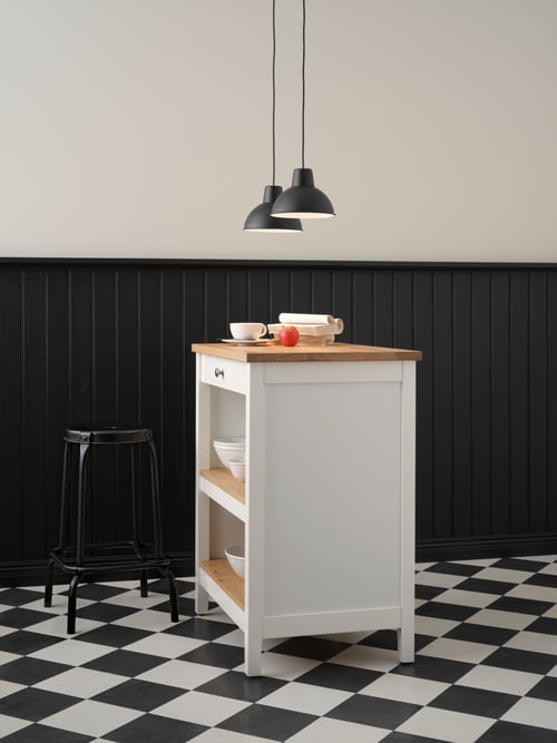 Kitchen area with tiled floor with a kitchen island with bowls, and a stool to the side, placed beneath two pendant lamps.