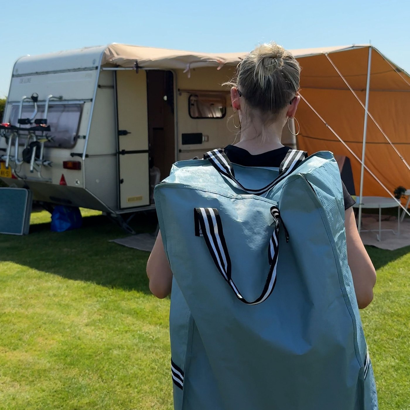 Someone is walking towards a caravan with a GÖRSNYGG bag on het back.