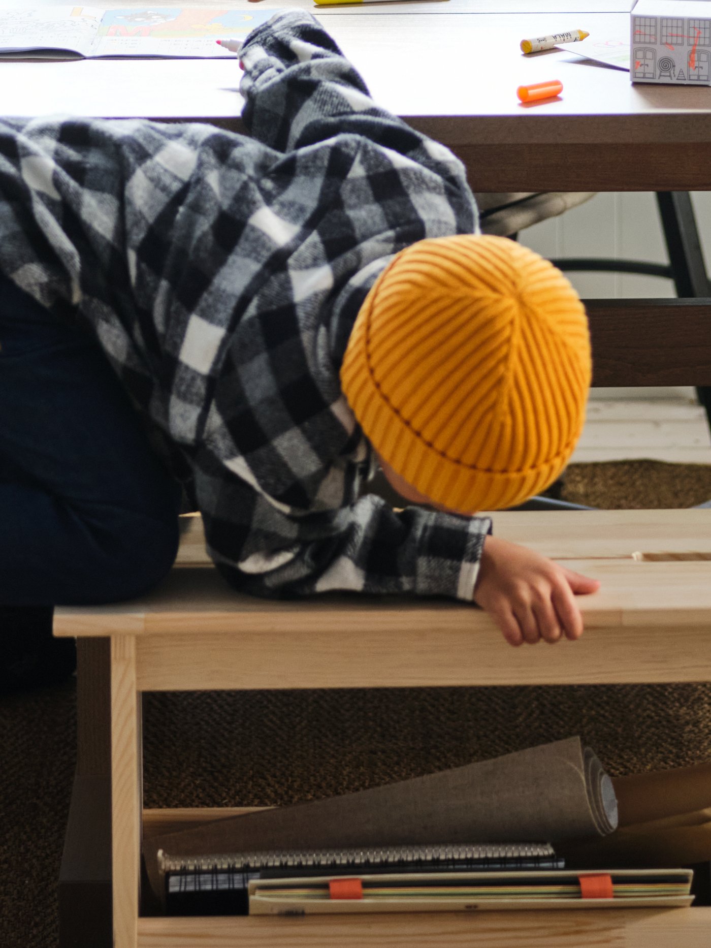 A young boy leans over the side of a PERJOHAN pine bench and peers down into its semi-filled storage compartment.