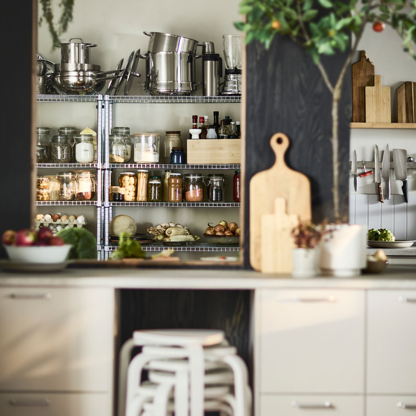 OMAR shelving units organise food, pots and pans in a kitchen with white base cabinets and black walls.