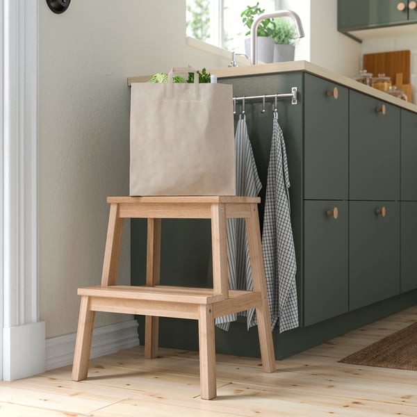 A BEKVAM step stool next to a green kitchen cabinet.