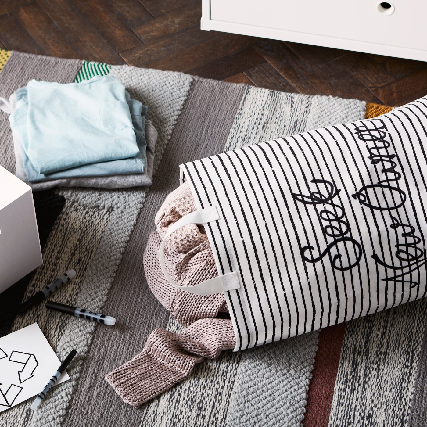 A white/black KLUNKA laundry bag in the bedroom